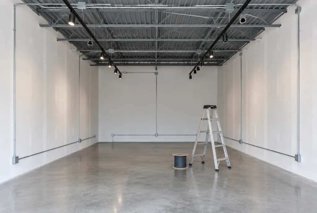 Empty commercial unit under renovation with surface conduit, junction boxes and track lighting